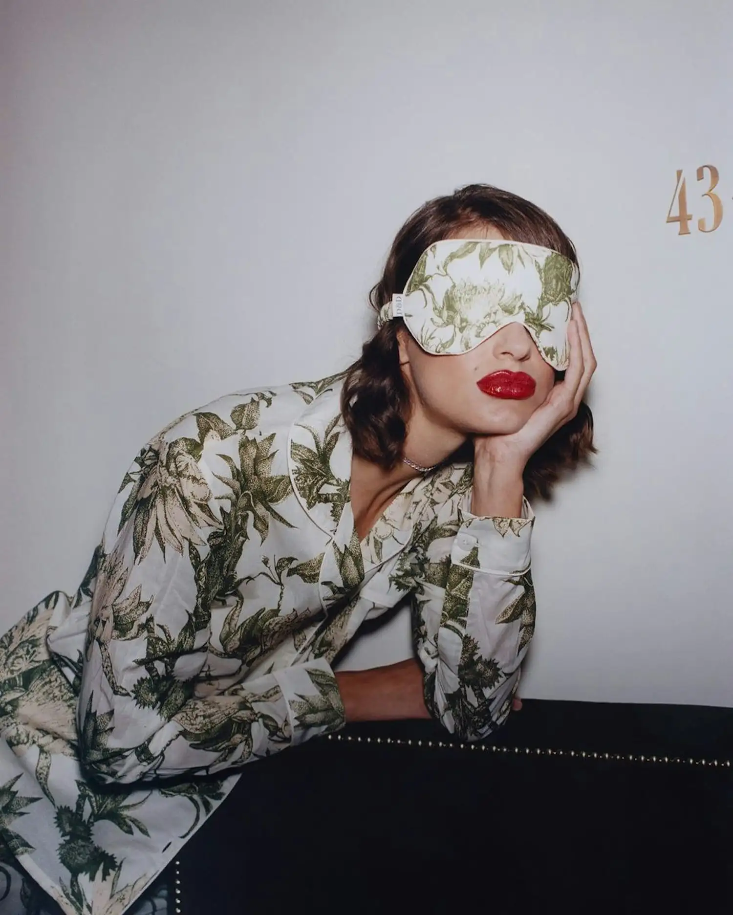 a woman in a green dress with a blindfold on her face